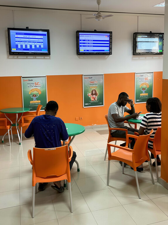 Salle de jeux SportCash avec tables, clients et écrans d’information