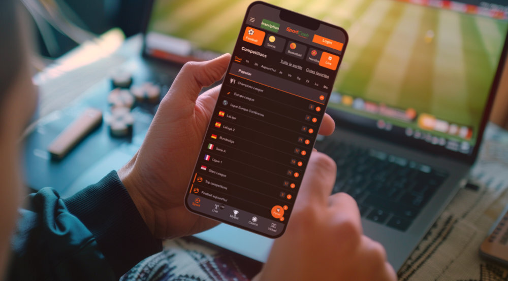 Smartphone avec une application de paris sportifs devant un écran affichant un match de football